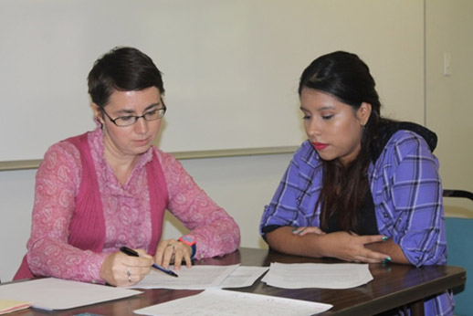 Professor demonstrating something in a book to a student.