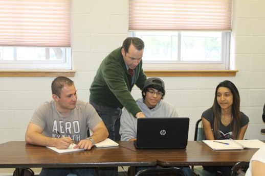 Professor showing students something on a laptop.